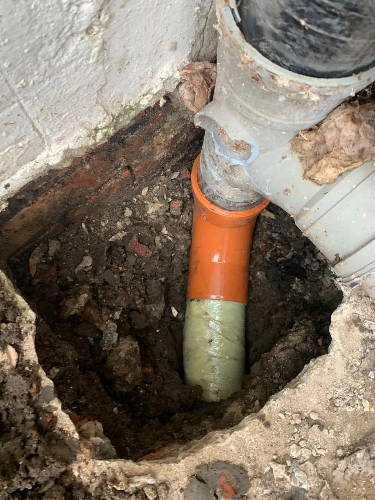 A professional drain relining repair in Durham, showing a new pipe liner and orange plastic connection